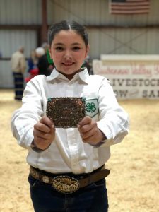 4H Member Miley McCray proudly displaying her 1st place belt buckle