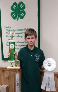 Lafayette 4H member Peyton Ditter holding a tropy and ribbons he won during a competition