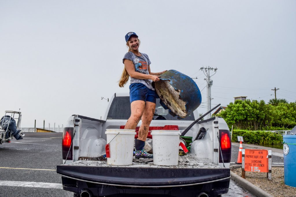 a volunteer holding trash and smiling