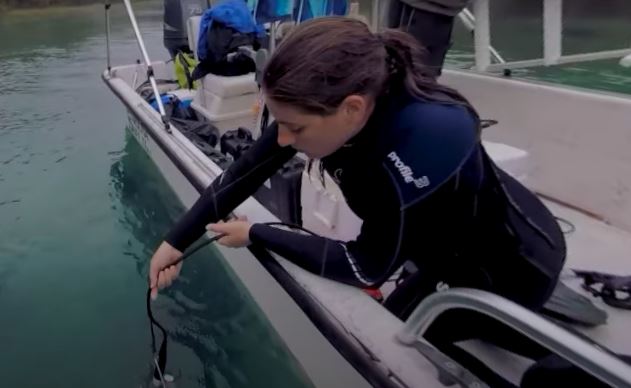 woman holds water quality meter over the side of a boat