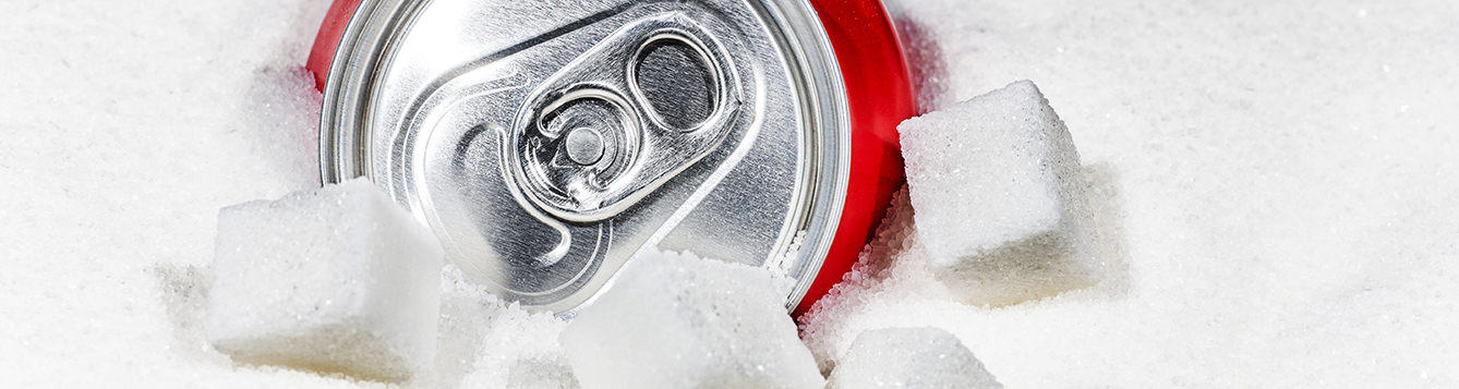 Can of soda surrounded by sugar and several sugar cubes