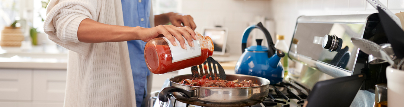 Woman pouring tomato sauce into a pan