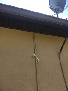 rain sensor hanging by wires below the roof overhang