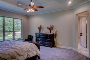 Bed room with ceiling fan and lights on.