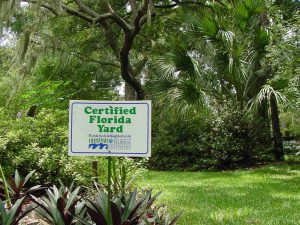 Landscape with trees and shrubs and sign that reads Certified Florida Yard.