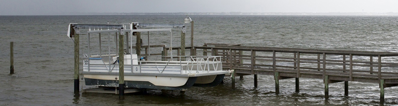 a pontoon boat on a boat lift, with a threatening storm in the distance.