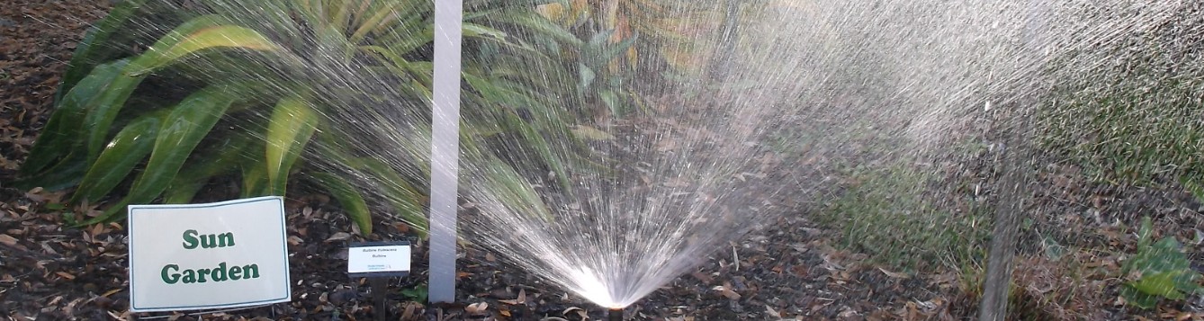 Pop up irrigation sprinkler and sign that reads "sun garden".