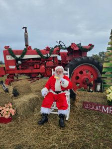 santa clause sitting in front of tractor eating sweet corn