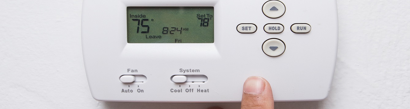 A wall home thermostat being adjusted