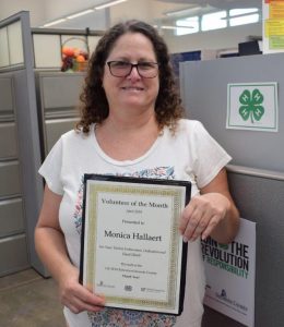 Monica Hallaert poses with her "Volunteer of the Month" plaque.
