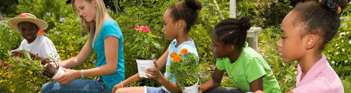 Children learning to garden from an adult