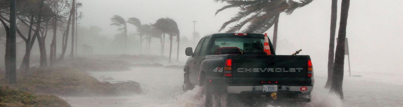 a government pickup drives along a rapidly flooding coast during a storm
