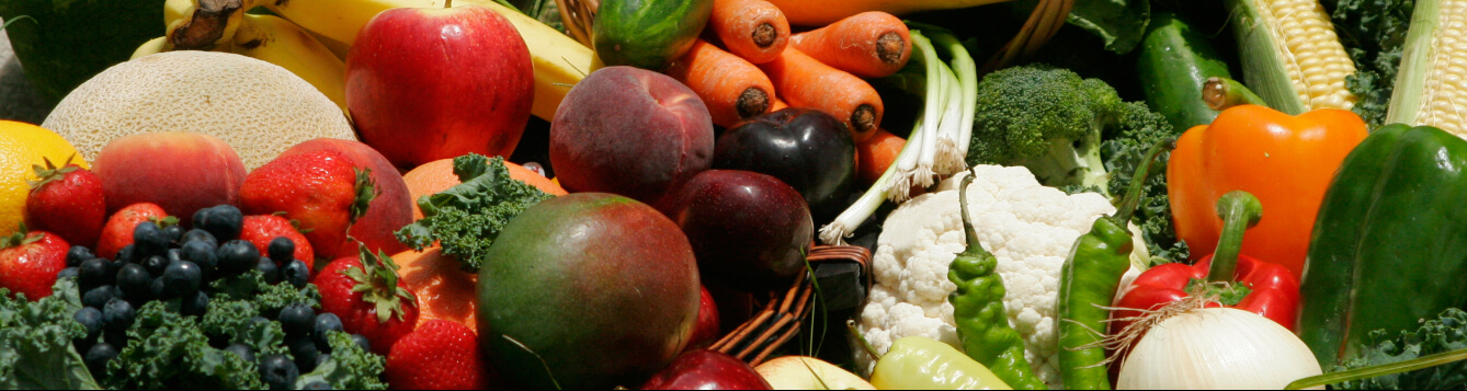 various fruits and vegetables arranged for photographic display, including apples, carrots, bananas, peppers, mangos and more