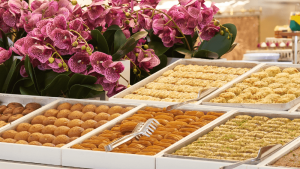 Sweet baked goods line a market display, alongside a colorful plant display. [CREDIT: pixabay.com]