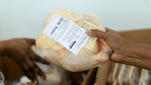 A shopper grabs a whole, frozen chicken from a display case at a grocery store. [CREDIT: UF/IFAS, Tyler Jones]