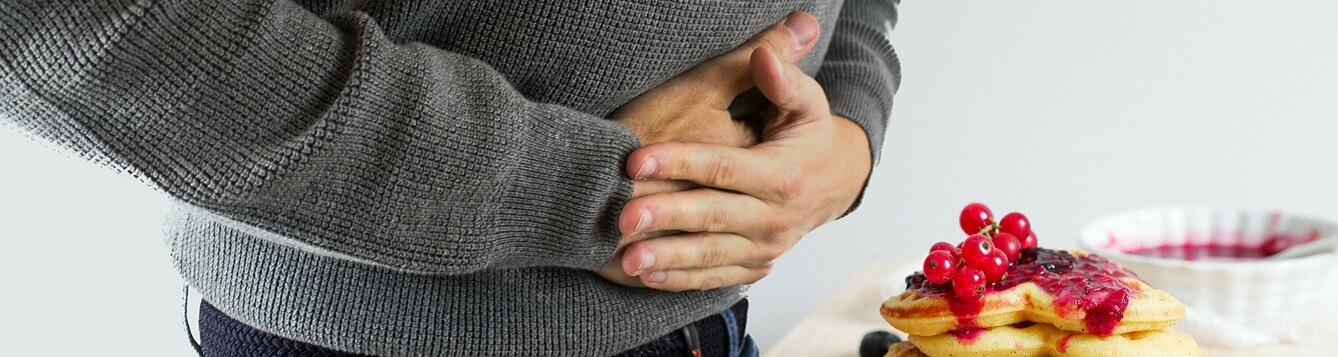 A man clasps his hands over his stomach, in apparent pain. [CREDIT: pxhere.com]