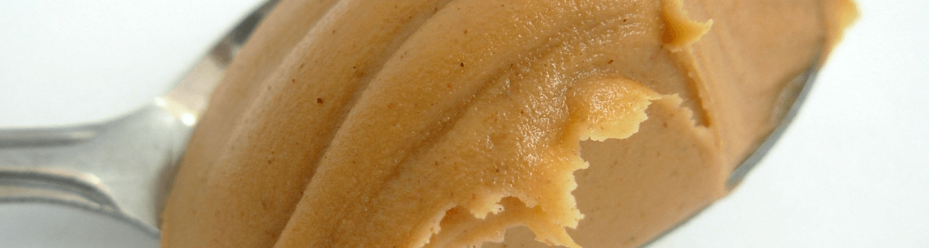 A closeup of a spoonful of peanut butter, against a white background. [CREDIT: pxhere.com]