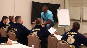 man talks to group of FFA students in conference room.