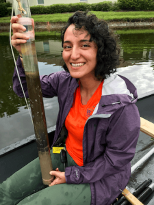 College student on boat holding a soil sediment sample.