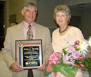 man and woman holding certificate and flowers