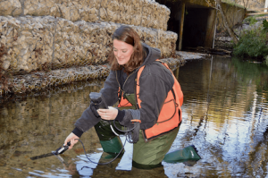 scientist in urban stream with water monitoring device