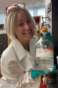 college student in lab holding bottle of sulfuric acid