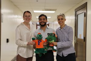 Two graduate students and one faculty member posing with the AEC AttaGator stuffed alligator 