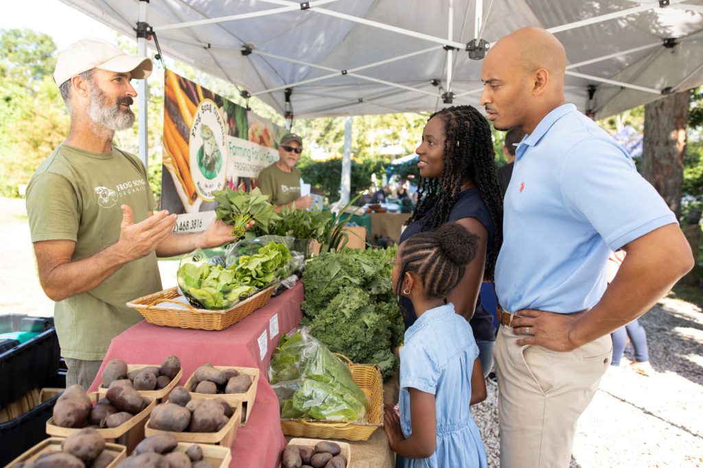 A family shopping for vegetables at a farmers market.