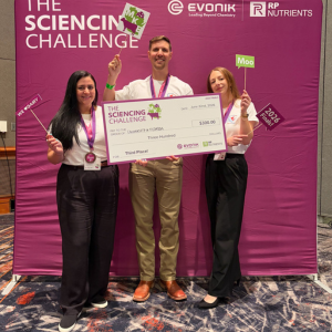 Amanda Ojeda, Nicholas Kertz, and Jessica Xhumari stand in front of purple banner that reads The Sciencing Challenge. They are holding a giant check awarded for placing third in the Sciencing Challenge Pitch Competition.