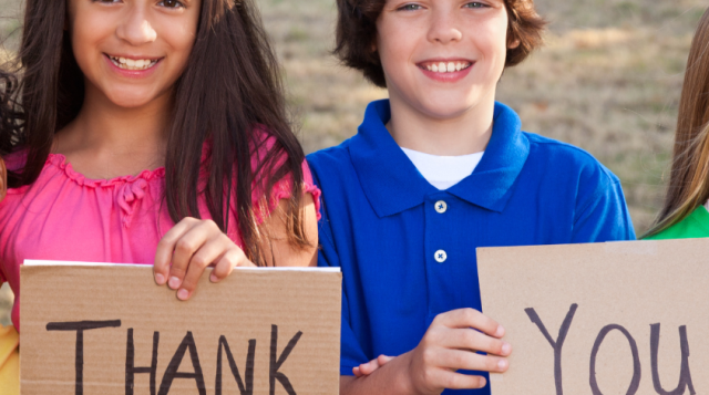 4 youth holding two pieces of card board that say "thank" and "you"