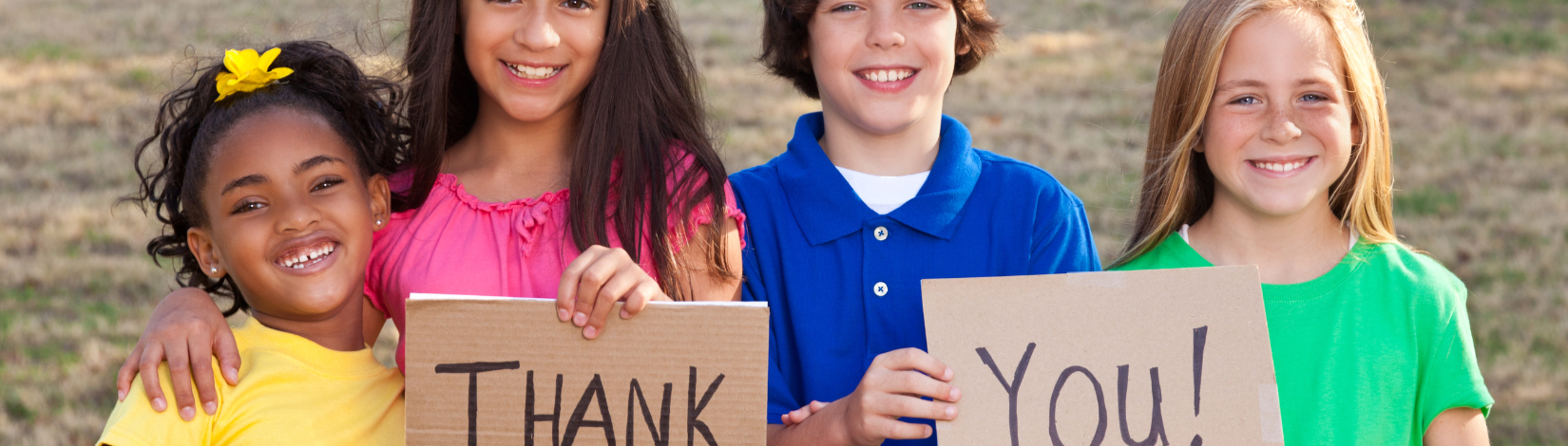 4 youth holding two pieces of card board that say "thank" and "you"