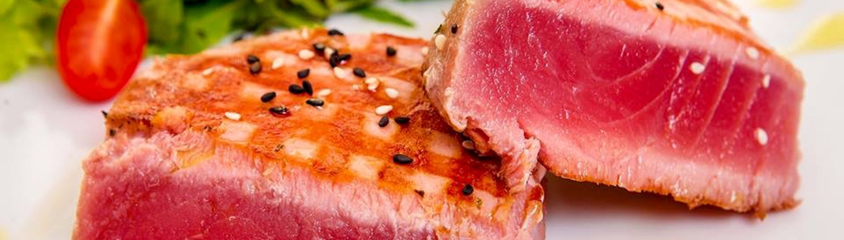 Seared tuna on a cutting board with a salad in the background
