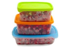 frozen strawberries in plastic containers with colorful lids