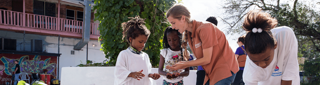 UF/IFAS Extension agent helps two girls plant seeds in a garden