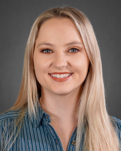 Portrait of blonde woman in gray striped shirt.