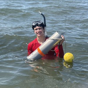 Student in lake holding core tool. 