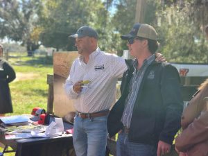 two men talking to group in field