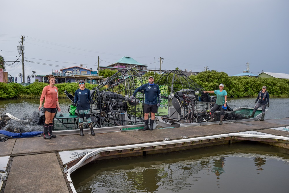 volunteers stand in front of their boats after the cleanup