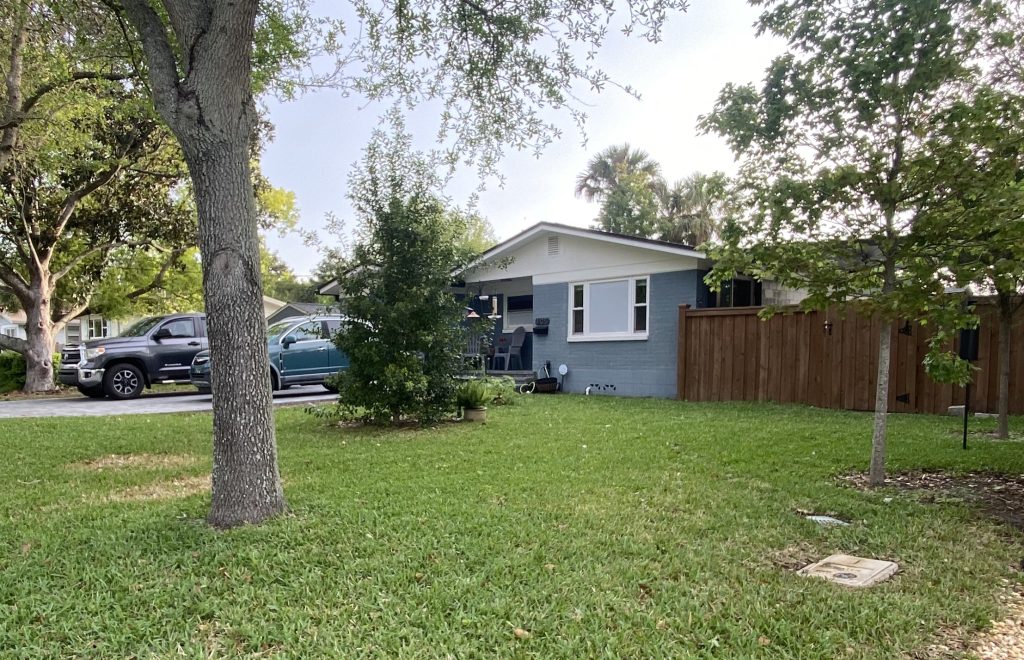 front yard with grass and a few small trees