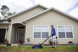 A man mowing a lawn in front of a suburban home. Photo taken on 03-31-17. UF/IFAS Photo by Camila Guillen