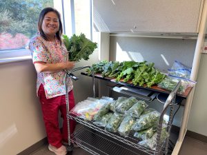 A nurse in scrubs standing next to a display of produce.