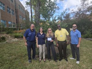 An award recipient and co workers stand in the garden