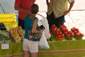 A local customer purchases fresh furits and vegetables from vender at the Downtown Farmer's Market in Gainesville, Florida. UF/IFAS Photo: Tyler Jones.