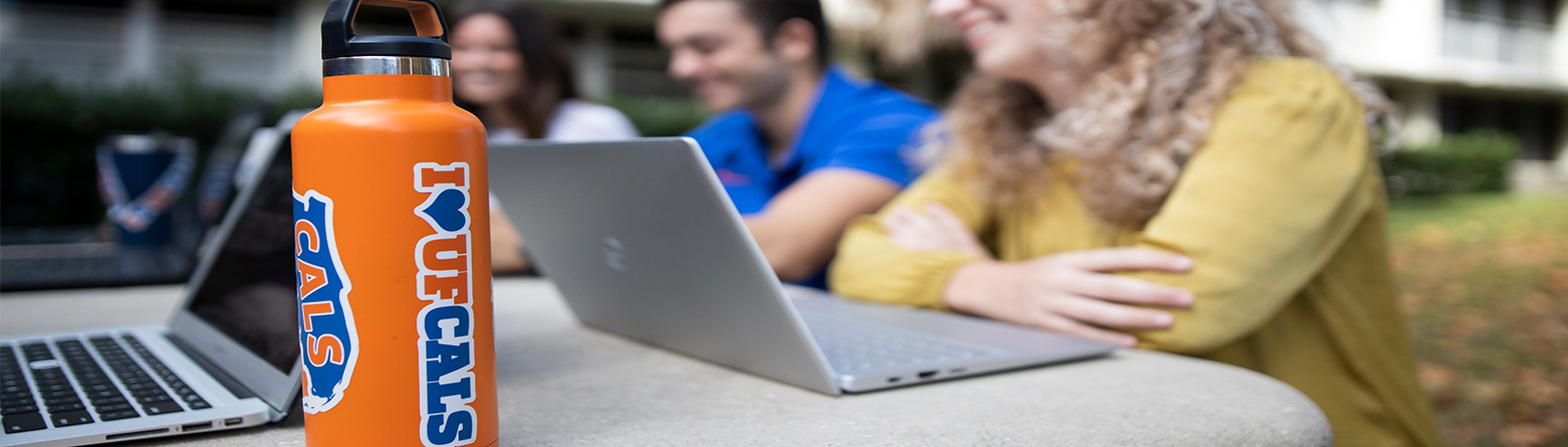 Water bottle with CALS stickers on a table where students are studying and working on laptops together. Photo taken 10-27-21.