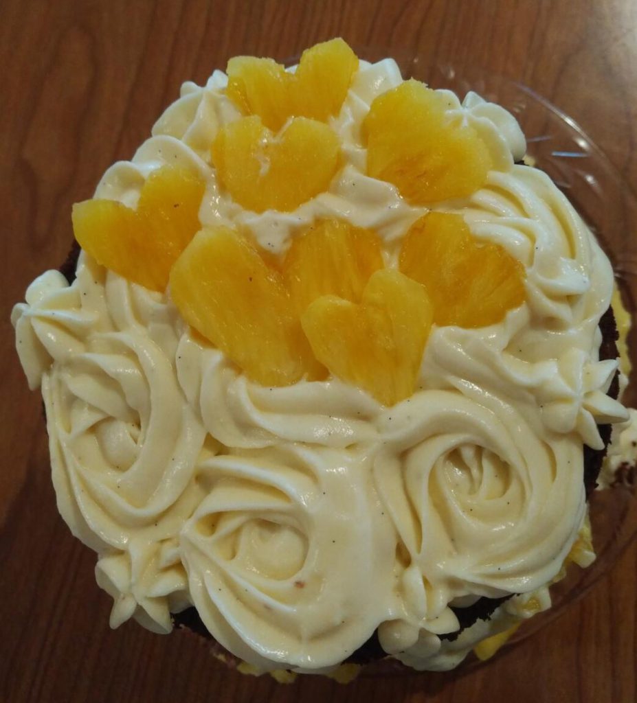 Photo of the top of a cake with pineapple hearts and rose-swirls in creme diplomat