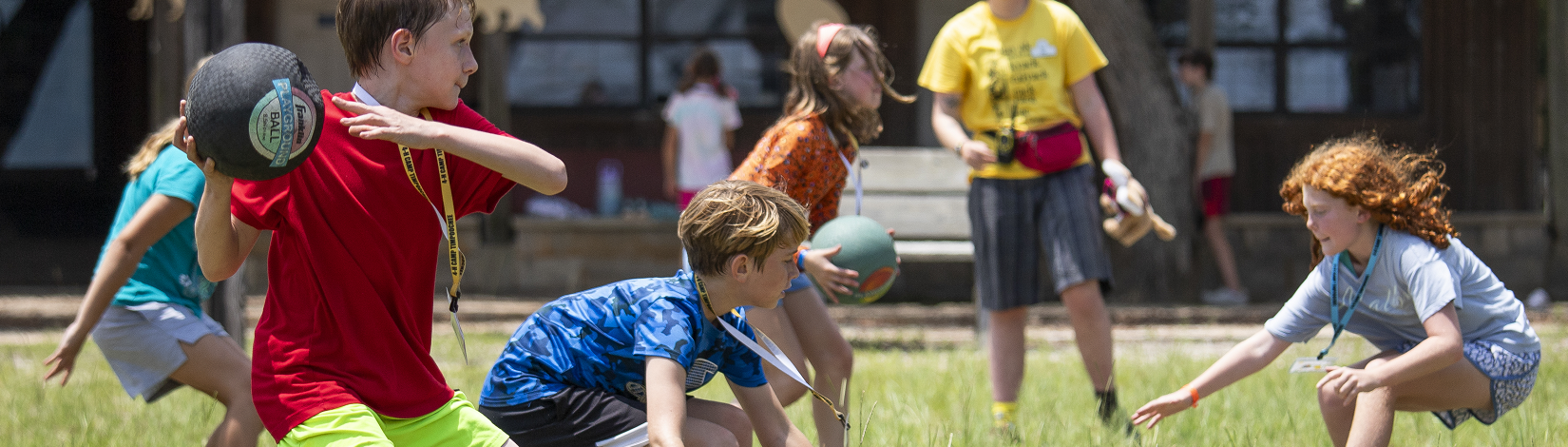 4-H youth playing dodgeball in a field.
