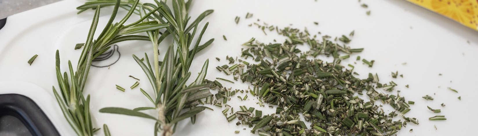 Kitchen knife, cutting board, and whole and chopped rosemary. Photo taken 05-01-23.