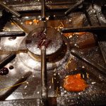 Gas stove top grill covered in crumbs and stains
