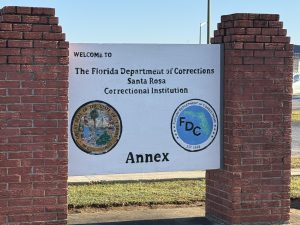 Brick columns holding a sign marking the Florida Department of Corrections and state logos