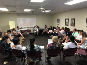 A group of people sit in a circle of chairs